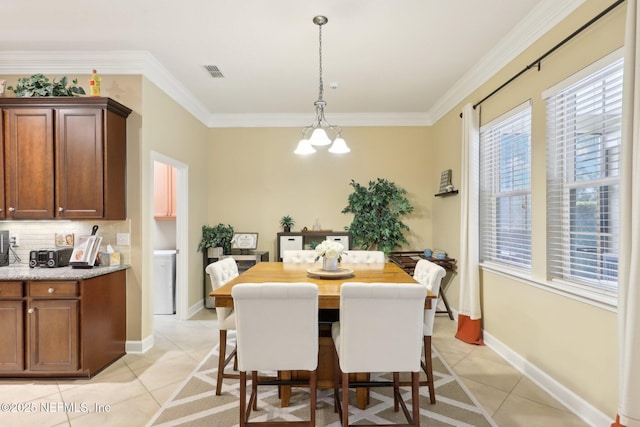 dining space with crown molding, a notable chandelier, and light tile patterned floors