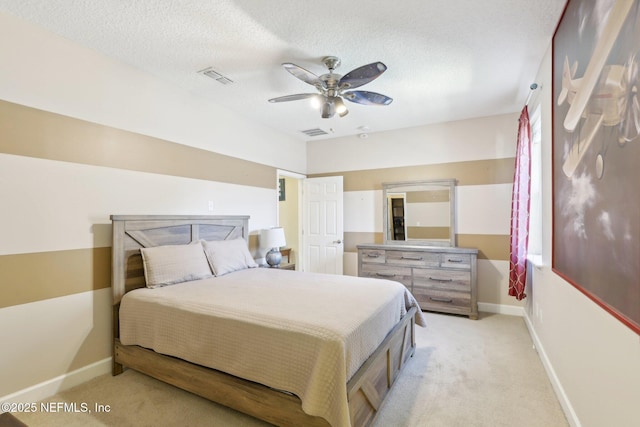 bedroom featuring ceiling fan, light colored carpet, and a textured ceiling