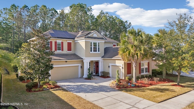 view of front of house featuring a garage, a front lawn, and solar panels