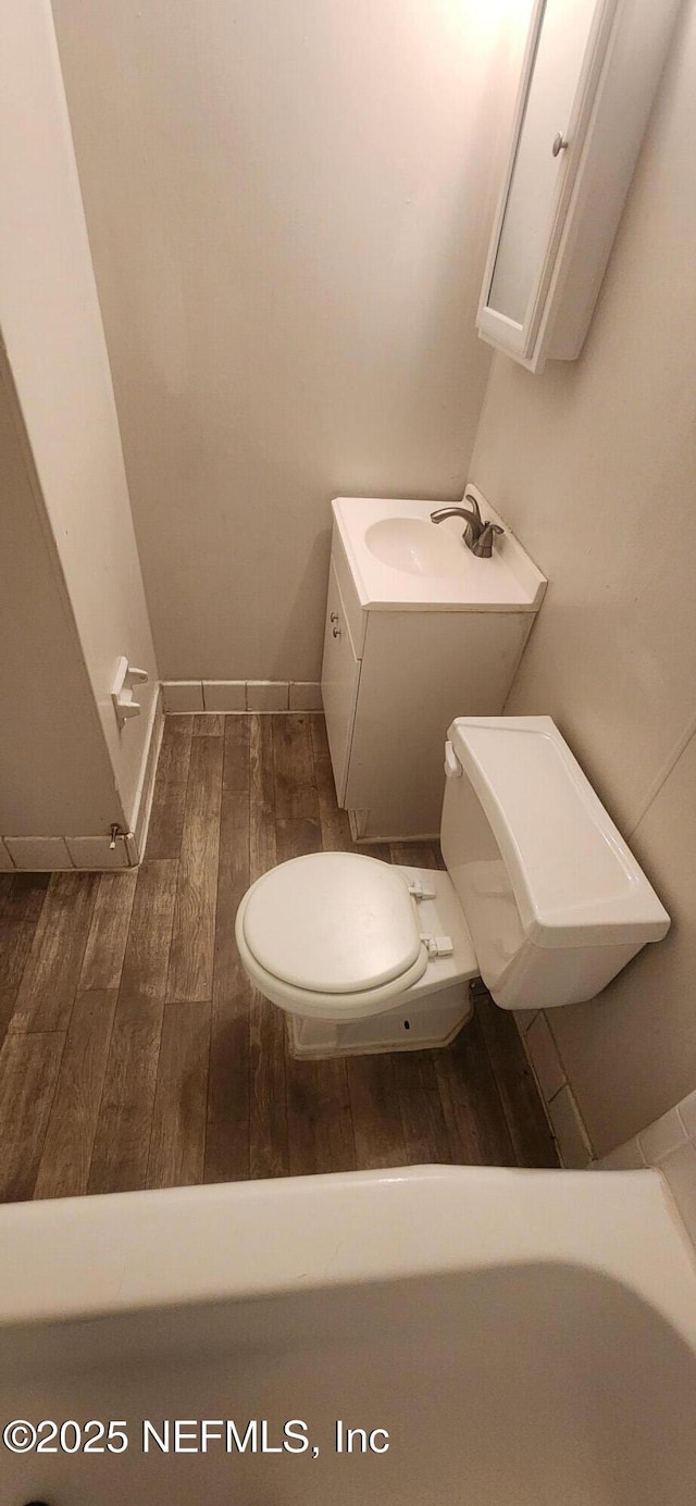 bathroom with toilet, vanity, and wood-type flooring