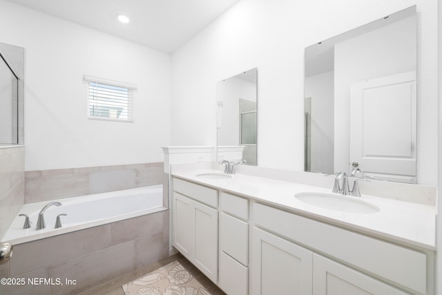 bathroom featuring vanity and tiled tub