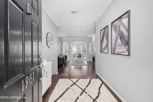 hall with ornamental molding, dark wood-type flooring, and a textured ceiling