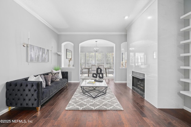 living room with crown molding, dark hardwood / wood-style floors, a textured ceiling, and a notable chandelier