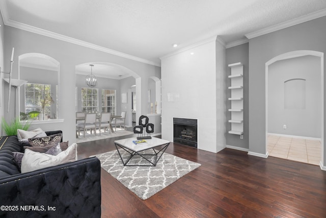 living room with an inviting chandelier, crown molding, dark wood-type flooring, and a textured ceiling