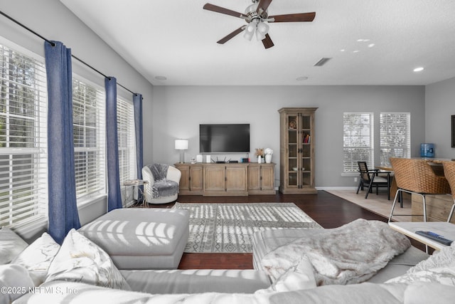 living room featuring dark wood-type flooring, a wealth of natural light, a textured ceiling, and ceiling fan