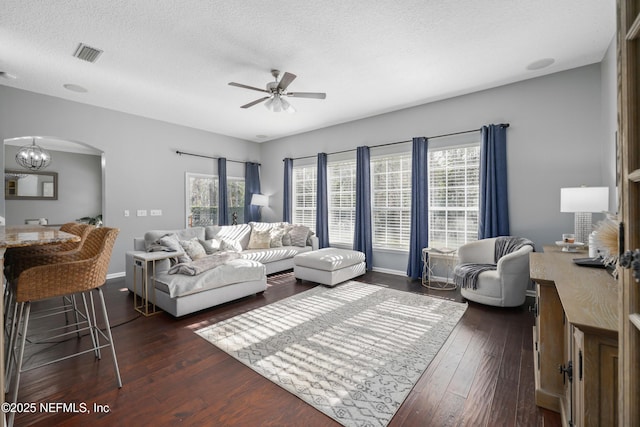 living room with dark hardwood / wood-style flooring, ceiling fan with notable chandelier, and a textured ceiling