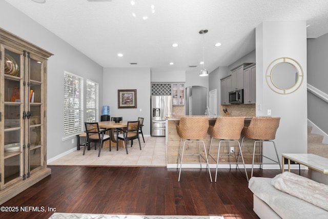 kitchen with a kitchen breakfast bar, stainless steel appliances, tasteful backsplash, kitchen peninsula, and light wood-type flooring