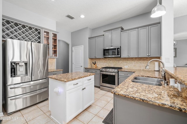 kitchen featuring sink, tasteful backsplash, decorative light fixtures, a textured ceiling, and stainless steel appliances