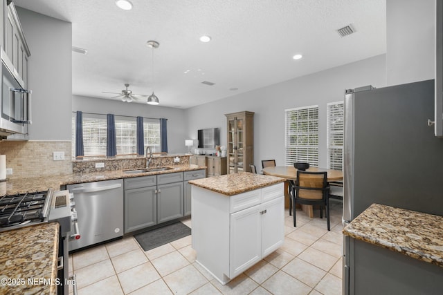 kitchen featuring sink, gray cabinetry, light tile patterned floors, a kitchen island, and stainless steel appliances