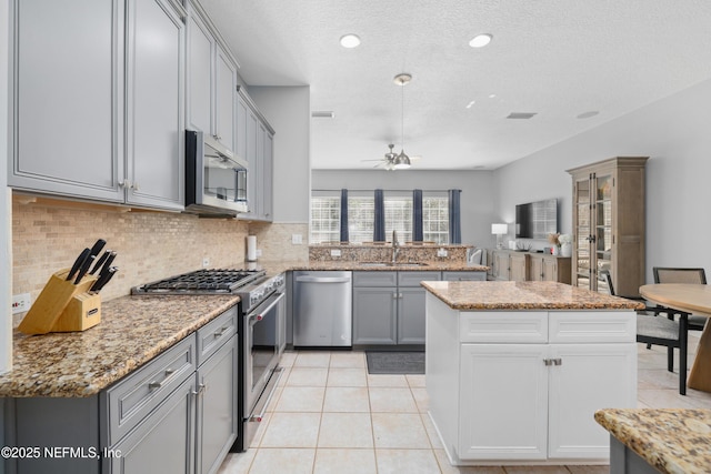 kitchen featuring light tile patterned flooring, sink, decorative backsplash, kitchen peninsula, and stainless steel appliances