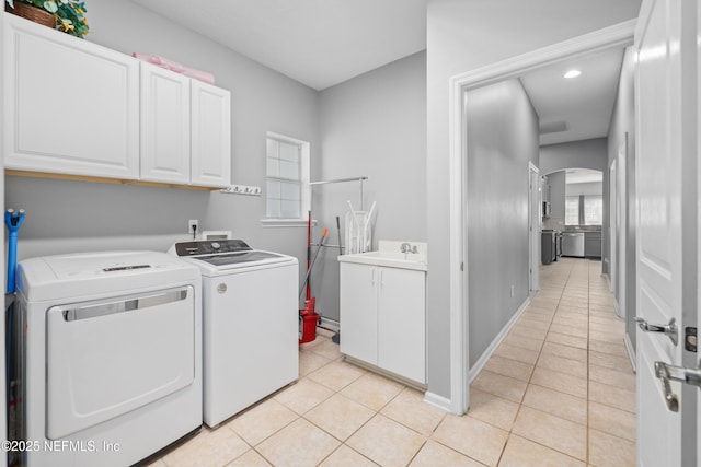 clothes washing area featuring independent washer and dryer, cabinets, light tile patterned flooring, and sink