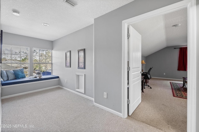 corridor with light colored carpet, vaulted ceiling, and a textured ceiling