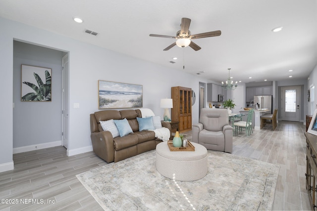 living room with ceiling fan with notable chandelier and light hardwood / wood-style floors