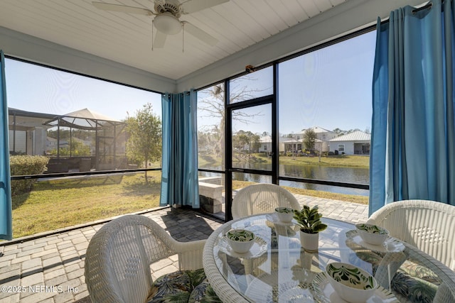 sunroom / solarium with ceiling fan and a water view