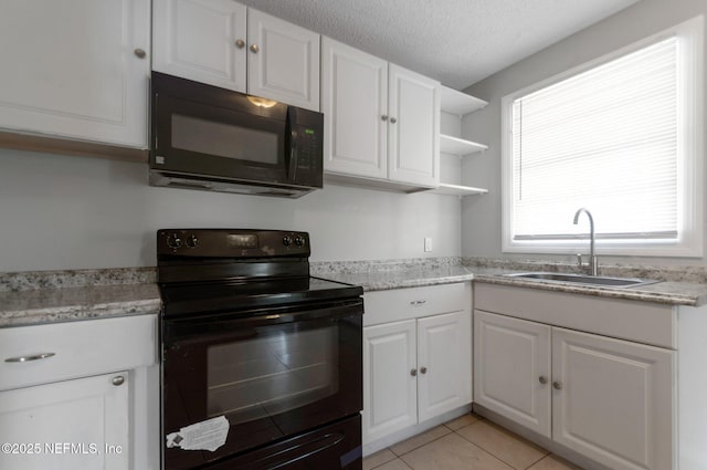 kitchen featuring a textured ceiling, light tile patterned floors, black appliances, white cabinets, and sink