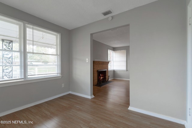 unfurnished living room with a textured ceiling and light hardwood / wood-style floors