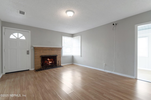 unfurnished living room featuring a textured ceiling and light hardwood / wood-style floors