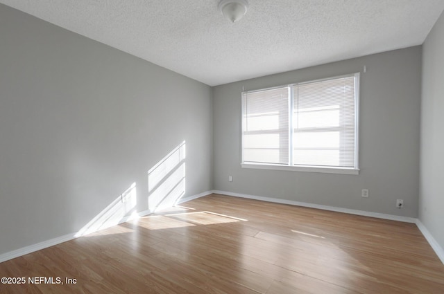 spare room with a textured ceiling and light hardwood / wood-style floors