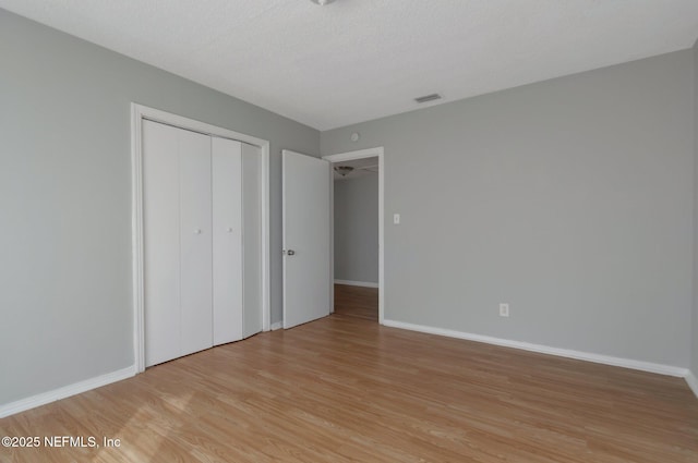 unfurnished bedroom with a closet, a textured ceiling, and light hardwood / wood-style flooring