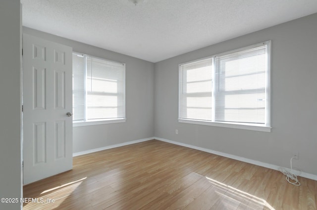 empty room featuring a textured ceiling and light hardwood / wood-style flooring