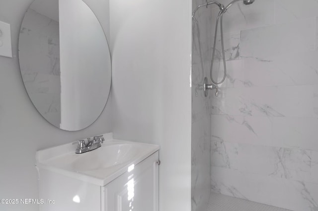 bathroom featuring tiled shower and vanity