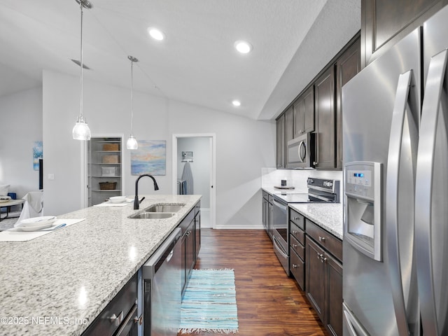 kitchen featuring stainless steel appliances, sink, decorative light fixtures, light stone counters, and lofted ceiling