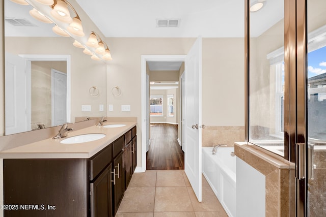 bathroom featuring a tub, a healthy amount of sunlight, tile patterned flooring, and vanity