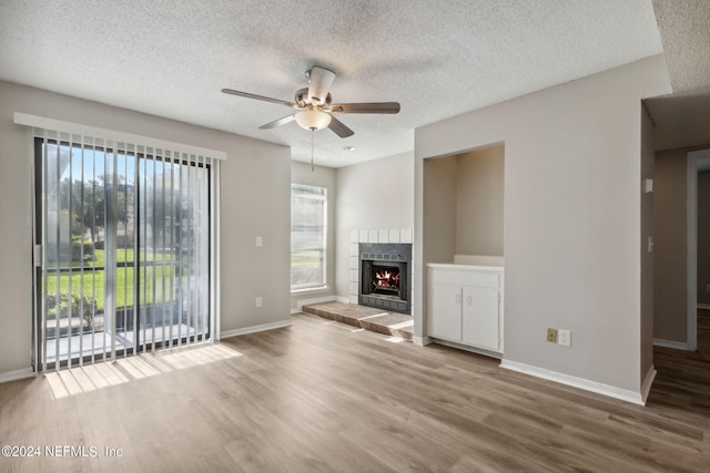 unfurnished living room featuring a textured ceiling, a fireplace, ceiling fan, and hardwood / wood-style flooring