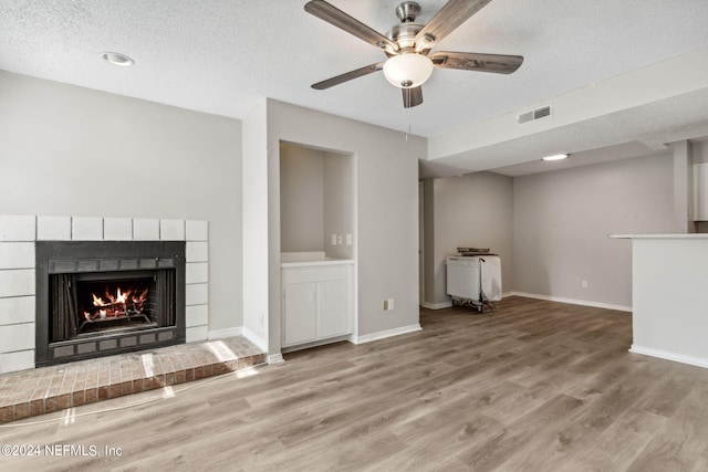 unfurnished living room featuring a fireplace, a textured ceiling, and hardwood / wood-style flooring