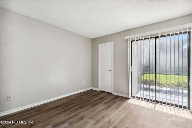 spare room featuring hardwood / wood-style flooring, a textured ceiling, and a wealth of natural light