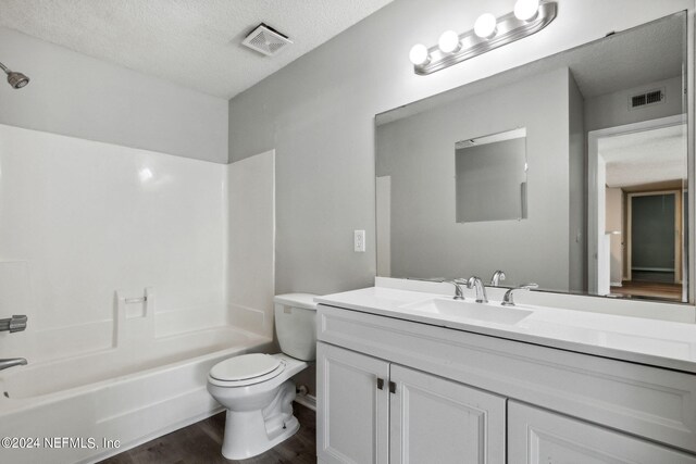 full bathroom with wood-type flooring, toilet, vanity, a textured ceiling, and shower / bathing tub combination