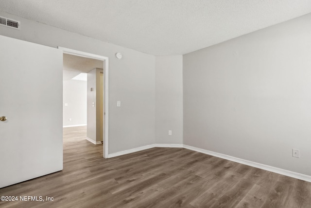 empty room featuring wood-type flooring and a textured ceiling