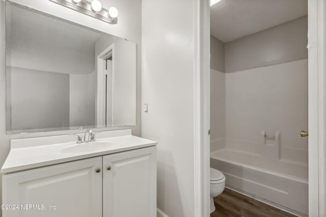 full bathroom featuring toilet, wood-type flooring, vanity, a textured ceiling, and shower / tub combination