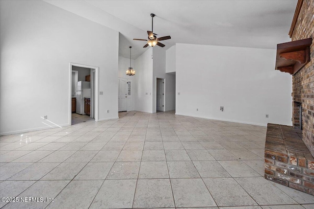 unfurnished living room with light tile patterned floors, ceiling fan with notable chandelier, a fireplace, and high vaulted ceiling