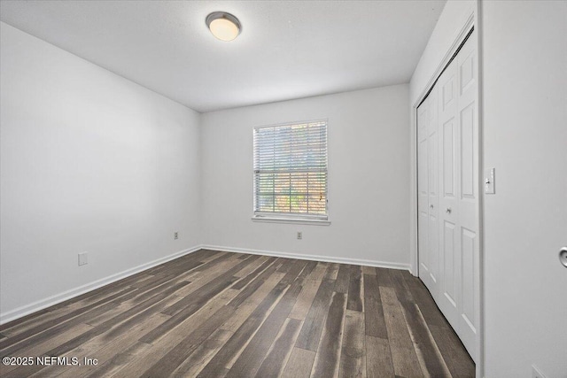 unfurnished bedroom featuring dark hardwood / wood-style floors and a closet