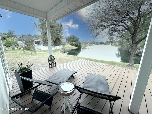 wooden deck featuring a water view and a lawn