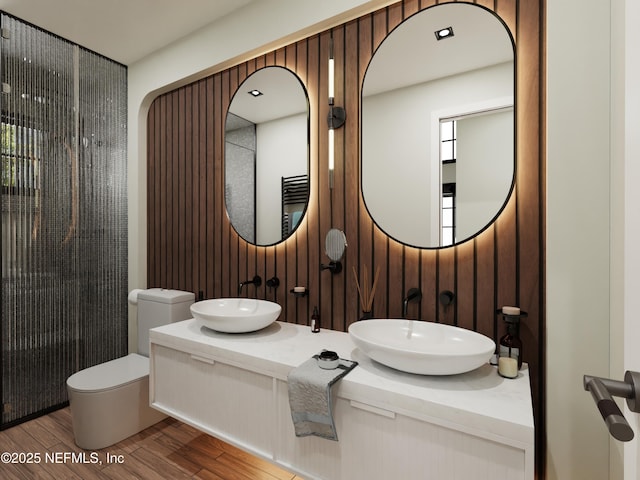 bathroom featuring wood walls, toilet, walk in shower, vanity, and hardwood / wood-style flooring