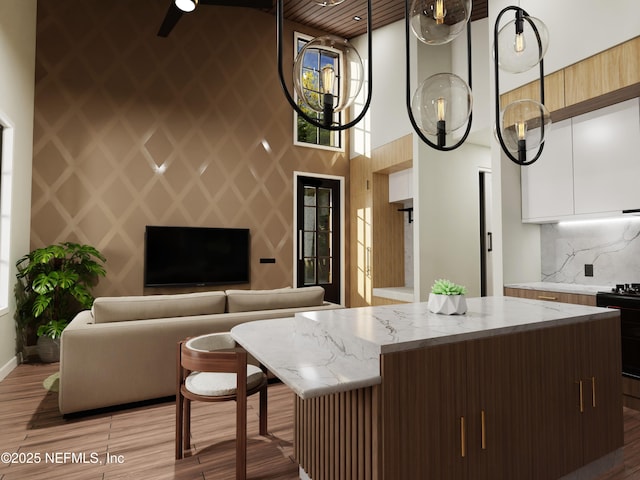 kitchen with a high ceiling, range, light stone counters, and dark brown cabinetry