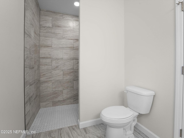 bathroom with tiled shower and toilet