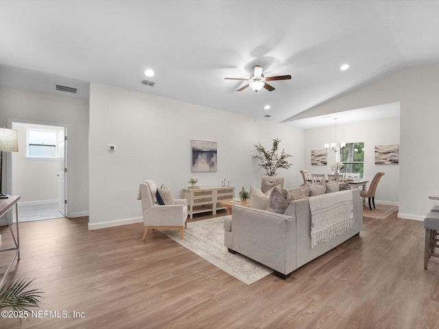 living room with light hardwood / wood-style floors, vaulted ceiling, and ceiling fan with notable chandelier