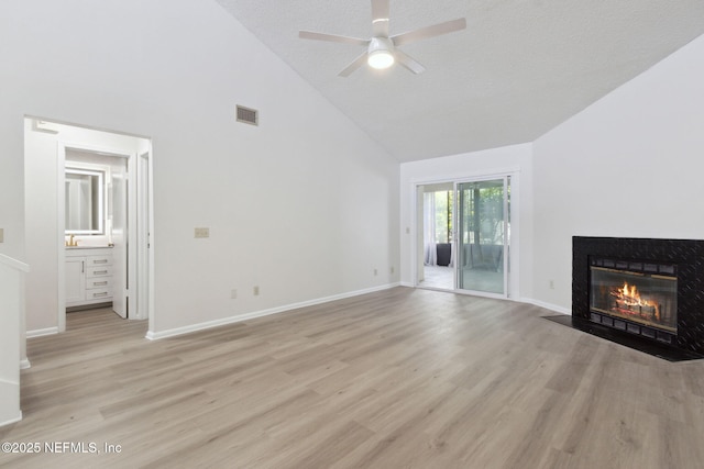 unfurnished living room featuring ceiling fan, a textured ceiling, high vaulted ceiling, and light wood-type flooring