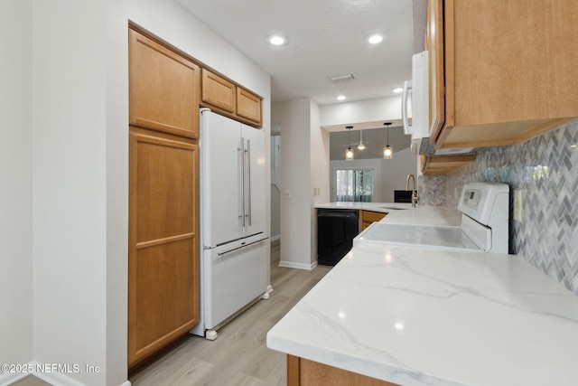 kitchen with white appliances, decorative light fixtures, sink, backsplash, and light hardwood / wood-style flooring