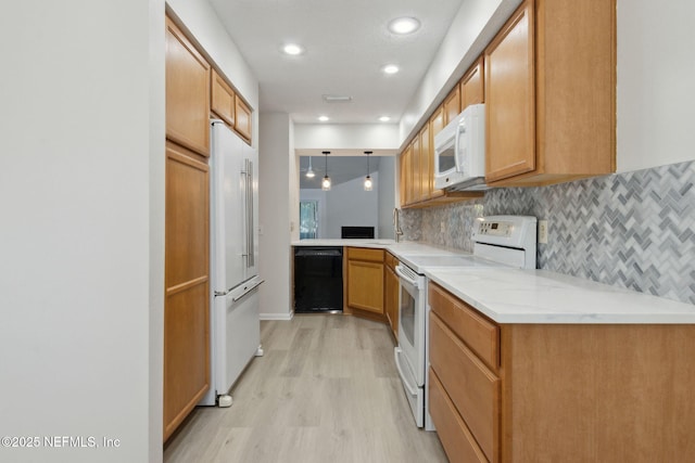 kitchen featuring decorative light fixtures, kitchen peninsula, decorative backsplash, white appliances, and light wood-type flooring