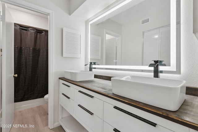 bathroom featuring hardwood / wood-style flooring, curtained shower, toilet, and vanity