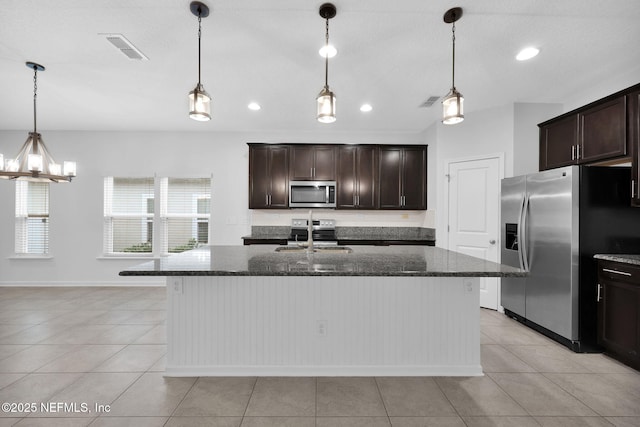 kitchen with a kitchen island with sink, sink, hanging light fixtures, and appliances with stainless steel finishes