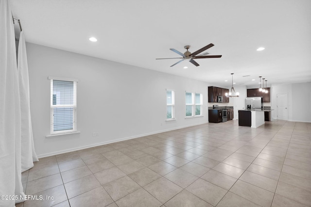 unfurnished living room with light tile patterned floors and ceiling fan with notable chandelier