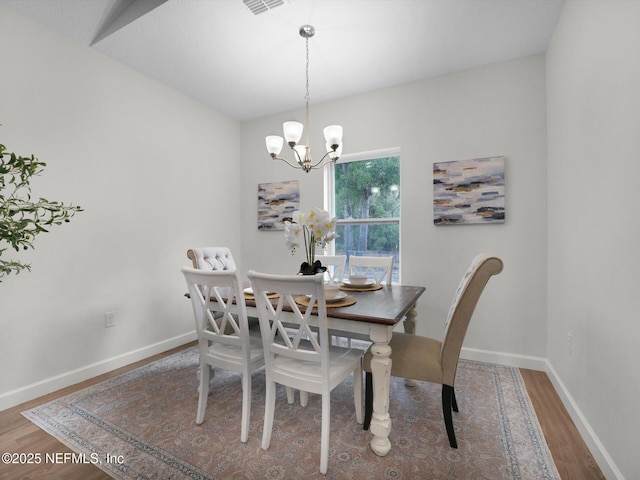 dining area featuring wood-type flooring, lofted ceiling, and a notable chandelier