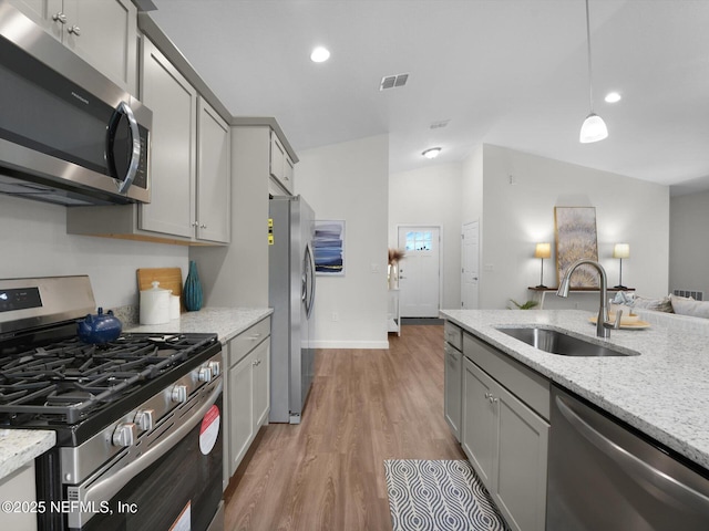 kitchen featuring hardwood / wood-style floors, appliances with stainless steel finishes, sink, hanging light fixtures, and gray cabinets