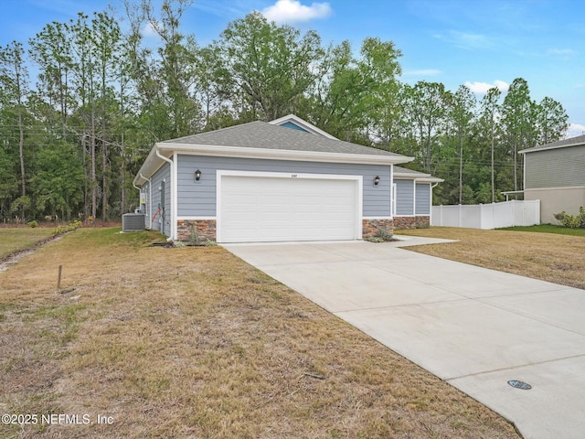 view of front of home with a garage, a front yard, and central AC