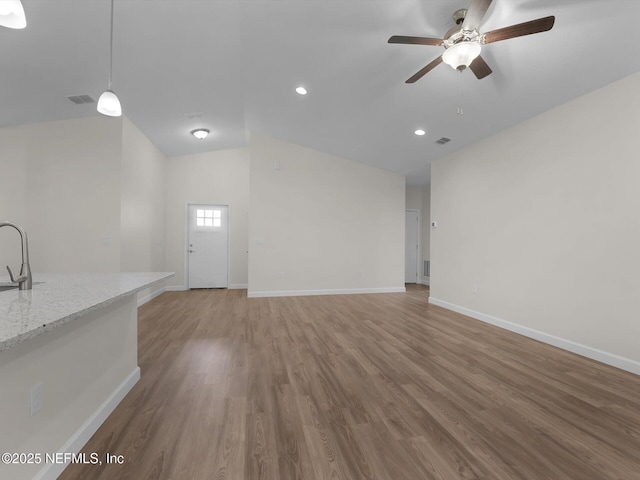 unfurnished living room featuring vaulted ceiling, ceiling fan, hardwood / wood-style floors, and sink